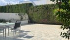 Sonnige Terrasse mit Gartenmöbeln, Fliesenboden und hoher Hecke beim Reihenhaus in Llucmajor
