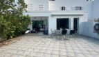 Sonnige Terrasse mit Esstisch und Stühlen, Markise und großen Glastüren zum Wohnbereich, weißes Reihenhaus Llucmajor