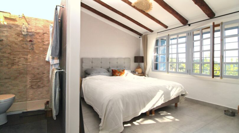 Helles Schlafzimmer mit Doppelbett, Holzbalkendecke, Ensuite-Bad und großen Fenstern in Bergjuwel Esporles