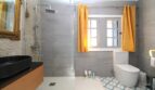 Modernes Badezimmer mit Regendusche, schwarzem Waschbecken und gelben Vorhängen im Berghaus Esporles