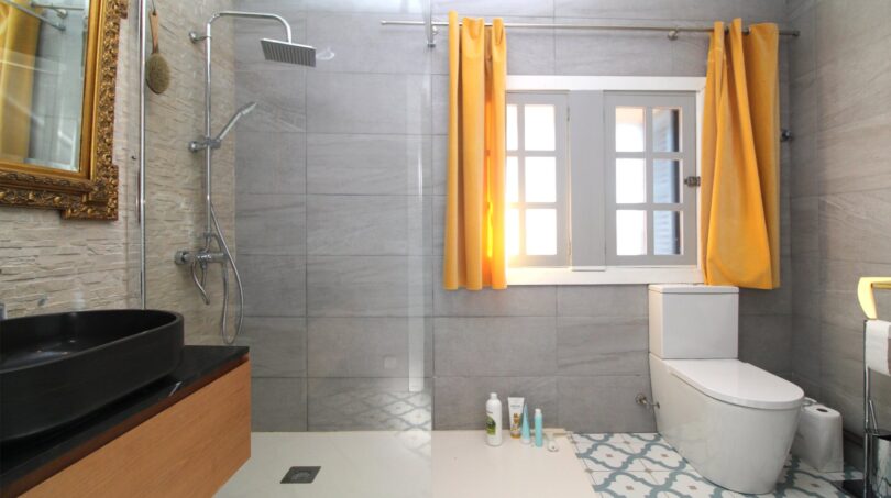 Modernes Badezimmer mit Regendusche, schwarzem Waschbecken und gelben Vorhängen im Berghaus Esporles