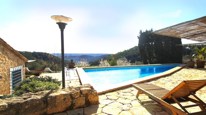 Außenpool mit Sonnenliegen, Natursteintetrasse und Panoramablick auf die Berge von Esporles, Mallorca.