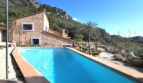 Außenpool einer Finca in Esporles mit Natursteinhaus, Palme und Bergpanorama