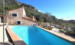 Außenpool einer Finca in Esporles mit Natursteinhaus, Palme und Bergpanorama