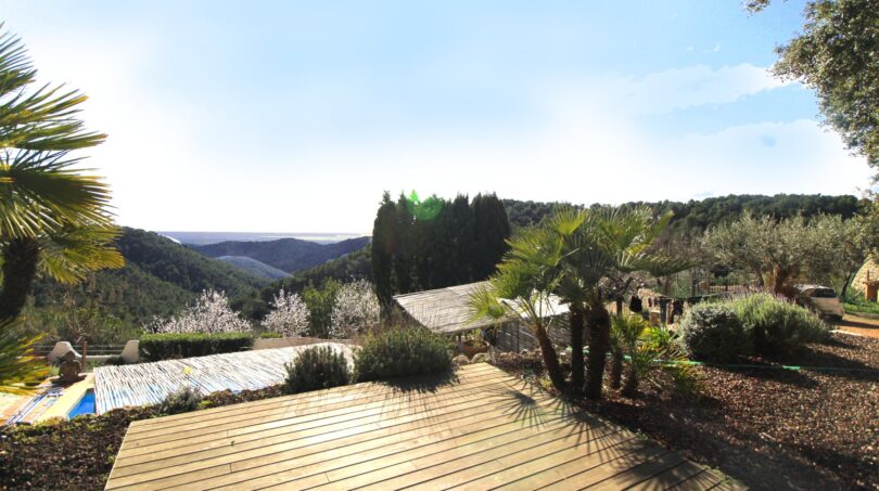 Holzterrasse mit Palmen, Pool und Panoramablick auf die Berglandschaft der Immobilie in Esporles
