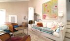 Helles Wohnzimmer mit weißem Kachelofen, gemütlichem Sofa und farbenfrohem Kunstwerk in Bergjuwel Esporles