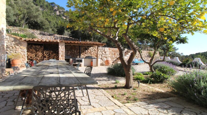 Rustikale Terrasse mit Holztisch, Zitronenbaum und Steinmauer beim Bergdomizil in Esporles