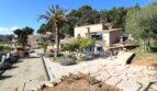 Rustikale Finca in Esporles mit Natursteinmauern, Palme, mediterranem Garten und gepflastertem Innenhof.