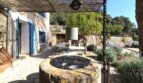 Rustikaler Innenhof mit antikem Steinbrunnen, Pergola und blauem Fensterläden in Bergjuwel Esporles