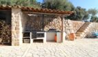 Rustikale Außenküche mit Steinmauern, Holzofen und Terrakottafliesen der Berghütte in Esporles