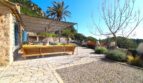 Mediterrane Terrasse mit Natursteinboden, Loungesofa und Pergola, umgeben von Palmen und Bergkulisse in Esporles.