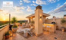 Luxuriöse Dachterrasse des Penthouse in Cales de Mallorca mit Outdoor-Bar, Loungebereich und Sonnenuntergang.