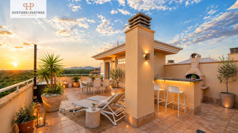 Luxuriöse Dachterrasse des Penthouse in Cales de Mallorca mit Outdoor-Bar, Loungebereich und Sonnenuntergang.