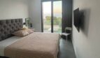 Modernes Schlafzimmer mit Doppelbett, Deckenventilator, Wand-TV und Meerblick durch Terrassentür in Cala Pi.