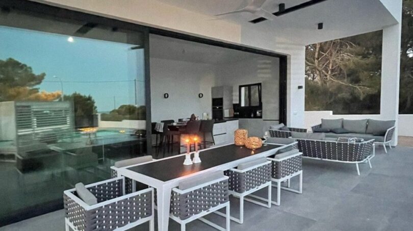 Moderne Terrasse mit Outdoor-Essbereich, Lounge und großen Glasfronten zum Innenbereich in Cala Pi