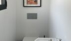 Modernes Gäste-WC mit wandhängendem WC, kleinem Waschbecken und Mallorca-Poster in Cala Pi.