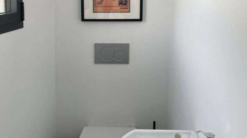 Modernes Gäste-WC mit wandhängendem WC, kleinem Waschbecken und Mallorca-Poster in Cala Pi.