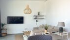 Helles Wohnzimmer mit Sandfarbtönen, Holzpendelleuchte, Wandmontiertem TV und modernen Designmöbeln in Cala Pi