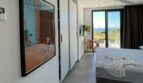 Modernes Schlafzimmer mit Meerblick, Deckenventilator, Mallorca-Kunstwerk und Zugang zur Terrasse in Cala Pi.