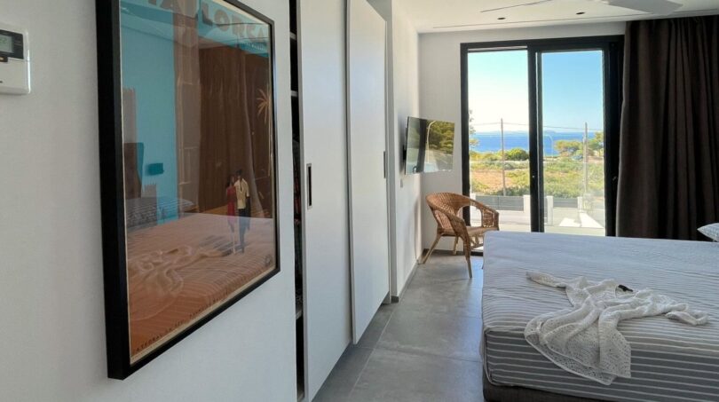 Modernes Schlafzimmer mit Meerblick, Deckenventilator, Mallorca-Kunstwerk und Zugang zur Terrasse in Cala Pi.