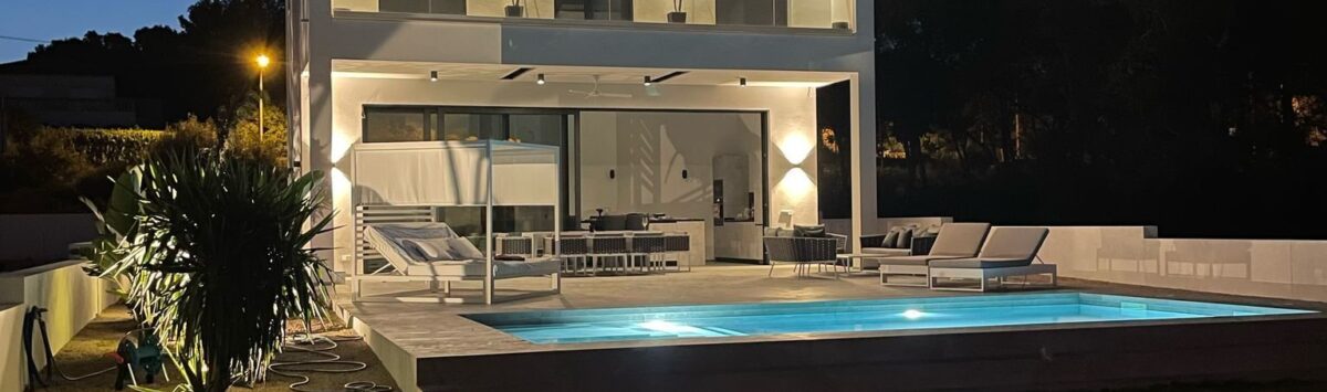 Moderne Villa in Cala Pi bei Nacht mit beleuchtetem Pool, Loungebereich und zweistöckiger weißer Fassade