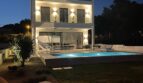 Moderne Villa in Cala Pi bei Nacht mit beleuchtetem Pool, Loungebereich und zweistöckiger weißer Fassade