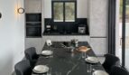 Modernes Esszimmer mit schwarzem Marmortisch, grauen Designerstühlen und offener Küche in Cala Pi