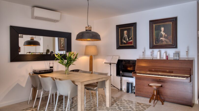 Esszimmer mit Holztisch, Klavier, klassischen Gemälden und Industrielampe im Stadthaus Alaró