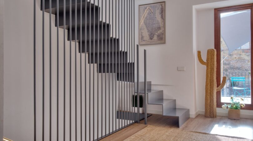 Modernes Treppenhaus mit Stahlgeländer, Holzboden und Kaktus-Deko im Stadthaus Alaró