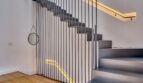 Modernes Treppenhaus mit grauer Betontreppe, schwarzem Metallgeländer und warmem LED-Licht im Stadthaus Alaró