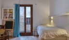 Helles Schlafzimmer mit Einzelbett, Balkon und türkisfarbenem Vorhang im modernisierten Stadthaus in Alaró.