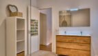 Modernes Badezimmer mit Holzwaschtisch, Doppelwaschbecken und weißem Regal im Stadthaus Alaró