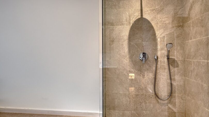 Modernes Duschbad mit Regendusche, Handbrause und Natursteinoptik-Fliesen im Stadthaus Alaró