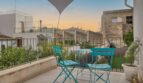 Dachterrasse mit türkisfarbenem Bistro-Set und Sonnensegel, Blick über die Dächer von Alaró bei Sonnenuntergang