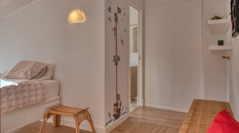 Kinderzimmer mit Hochmesserwand, Wolkenlampe, Holzboden und rotem Sitzsack im Stadthaus Alaró