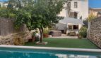 Área exterior con piscina, limonero y bañera de hidromasaje frente a casa adosada modernizada en Alaró