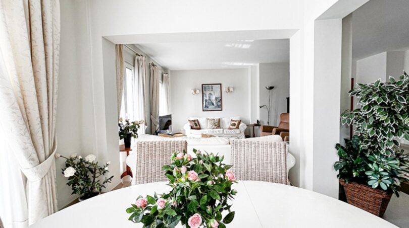 Bright dining room with white table, bouquet of roses and view into living room, Mediterranean villa Santa Ponça