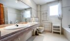 Bright bathroom with double washbasin on marble top, bathtub, toilet and two windows in Villa Santa Ponça