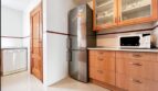 Modern kitchen with wooden fronts, stainless steel refrigerator and glass display cabinets in Santa Ponça