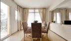 Bright dining area with rattan chairs, round table, terrace access and elegant curtains in Santa Ponça