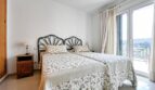 Bright bedroom with two single beds, floral bedding and balcony access with sea views in Santa Ponça