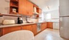 Bright kitchen with wooden fronts, built-in appliances and round dining table in Santa Ponça