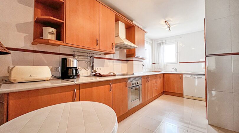 Bright kitchen with wooden fronts, built-in appliances and round dining table in Santa Ponça