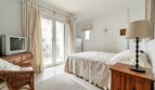 Bright bedroom with double bed, wooden furniture, balcony access and cream-colored curtains in Santa Ponça