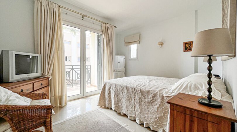 Bright bedroom with double bed, wooden furniture, balcony access and cream-colored curtains in Santa Ponça