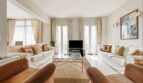 Bright living room with white sofas, brown armchairs, glass table and terrace doors in Santa Ponça