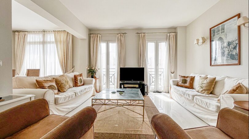 Bright living room with white sofas, brown armchairs, glass table and terrace doors in Santa Ponça