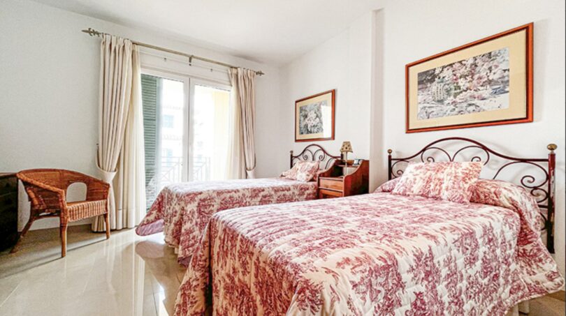 Bright double bedroom with two beds, red and white bedding, balcony and Mediterranean flair in Santa Ponça