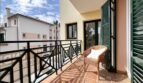 Sunny balcony with rattan chair, green shutters and view of Mediterranean neighboring buildings in Santa Ponça.