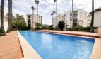 Communal pool with palm trees and white apartment buildings in Mediterranean residential complex in Santa Ponça